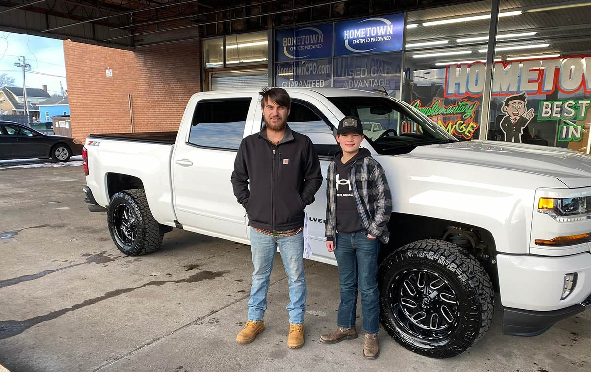 A teen and his father stand in front of the used truck they just bought from out Ironton, OH dealership